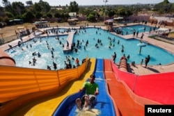 FILE - Palestinians play inside a swimming pool to cool down during a hot weather, in Khan Younis in the southern Gaza Strip, July 20, 2022.