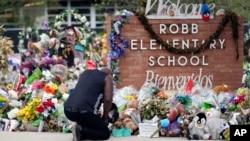 FILE - Reggie Daniels pays his respects a memorial at Robb Elementary School, June 9, 2022, in Uvalde, Texas, created to honor the victims killed in the recent school shooting. Two teachers and 19 students were killed in the mass shooting. 