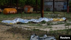 Обгорілі тіла в'язнів лежать накриті після обстрілу в СІЗО в селищі Оленівка Донецької області, Україна, 29 липня 2022 року.