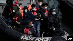 FILE - People thought to be migrants who undertook the crossing from France in small boats and were picked up in the Channel, arrive to be disembarked from a small transfer boat in Dover, south east England, June 17, 2022.