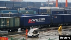 A worker stands next to a train carrying China Railway Express containers at Chongqing railway port station, March 30, 2019.