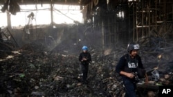 FILE - Journalists walk inside a destroyed warehouse for storing food, after an attack from Russia in Brovary, on the outskirts of Kyiv, Ukraine, March 29, 2022. 