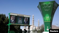 FILE - People sit under posters of Houthi leaders in Sanaa, Yemen, April 7, 2022.