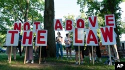 Demonstrators hold signs as they rally before the first Jan. 6, investigation hearing on Capitol Hill in Washington, June 9, 2022.