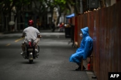 Seorang pekerja duduk di sebelah pagar yang didirikan untuk menutup area perumahan di tengah lockdown COVID-19 di distrik Huangpu, Shanghai. (Foto: AFP)