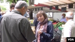 France Unbowed politician Sarah Legrain speaks to a voter in Paris' 19th neighborhood, one of the poorest and most ethnically mixed in the city. (Lisa Bryant/VOA)