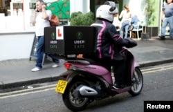 An UberEATS food delivery courier rides her scooter in London on September 7, 2016.