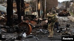 Vojnik koristi svoj mobilni telefon da snimi uništeni ruski tenk i oklopna vozila, usred ruske invazije na Ukrajinu u Buči, u regiji Kijev, Ukrajina, 2. aprila 2022. REUTERS/Zohra Bensemra