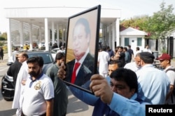 A Pakistani lawmaker holds a photo of former prime minister Nawaz Sharif as he walks towards the parliament house building to cast his vote on a motion of no-confidence to oust Prime Minister Imran Khan, in Islamabad, Pakistan April 3, 2022.
