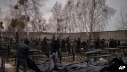Workers carry the body of people found dead to a cemetery in Bucha, outskirts of Kyiv, Ukraine, April 5, 2022.