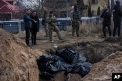 People stand next to a mass grave in Bucha, on the outskirts of Kyiv, Ukraine, April 4, 2022.