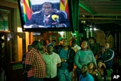 Zimbabweans watch a televised address to the nation by President Robert Mugabe at a bar in downtown Harare, Zimbabwe, Nov. 19, 2017.