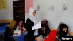 FILE - Kerishma Rasheedi, 16, reads during a class at a private school class in Kabul, Afghanistan, Aug. 3, 2022. 