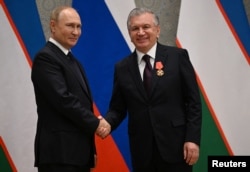 Presiden Rusia Vladimir Putin menganugerahkan Ordo Alexander Nevsky kepada Presiden Uzbekistan Shavkat Mirziyoyev dalam upacara di sela-sela KTT Organisasi Kerja Sama Shanghai (SCO) di Samarkand, Uzbekistan, 15 September 2022. (Foto: Sputnik/Dmitry Azarov via REUTERS)