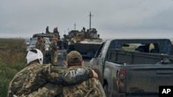 A Ukrainian soldier helps a wounded fellow soldier in the Kharkiv region, Ukraine, Sept. 12, 2022. Ukrainian troops retook a wide swath of territory from Russia on Monday, pushing back to the northeastern border in some places, and claiming to have captured many Russian soldiers.