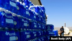 FILE- Tommy Gutierrez, Paiute, helps load water bottles that are distributed weekly to the Yerington Paiute tribe in Yerington, Nev.