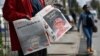 Pedestrians walk past a vendor selling local dailies carrying the headlines reporting the news of the death of Queen Elizabeth II, in Nairobi on Sept. 9, 2022.