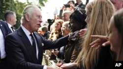 Britain's King Charles III meets the public near Lambeth Bridge as they wait to view Queen Elizabeth II lying in state ahead of her funeral in London, Sept. 17, 2022.