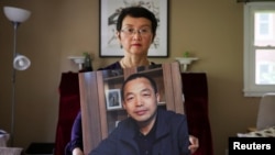 Sophie Luo Shengchun, the wife of jailed Chinese human rights lawyer, Ding Jiaxi, poses with a photo of him at her home in Alfred, New York, July 28, 2022.
