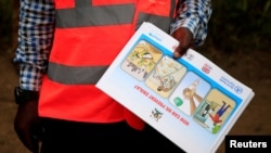 FILE - An Ugandan health worker shows an informational flyer on Ebola virus and how to prevent its spread to the community of Kirembo village, near the border with the DRC, in Kasese district, Uganda, June 15, 2019. 