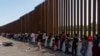 Sejumlah migran pencari suaka, yang kebanyakan berasal dari Venezuela dan Kuba, menunggu untuk dipindahkan oleh petugas Perbatasan dan Bea Cukai AS di area perbatasan AS-Meksiko di Eagle Pass, Texas, pada 14 Juli 2022. (Foto: Reuters/Go Nakamura)