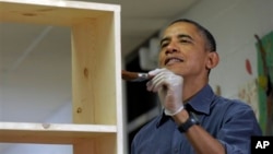 President Barack Obama stains a bookshelf at Burrville Elementary School as the first family participated in a community service project for the National Day of Service, part of the 57th Presidential Inauguration, in Washington, January 19, 2013.