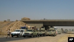 FILE - Iraqi security forces in uniforms and plainclothes head to Baghdad in the main road between Baghdad and Mosul, a day after fighters from the Islamic State of Iraq and the Levant took control of much of Mosul, June 11, 2014.