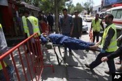 Afghan men carry a wounded man after the second blast in Kabul, April 30, 2018.