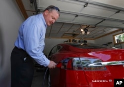 Jeff Solie plugs in his electric Tesla sedan at his home, in New Berlin, Wis., July 13, 2017. Electric cars are seeing growing support around the world. But there’s a problem: There aren’t enough places to plug those cars in.
