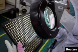 Seorang pekerja memeriksa cip semikonduktor di pabrik pengemasan cip Unisem (M) Berhad di Ipoh, Malaysia, 15 Oktober 2021. (Foto: REUTERS/Lim Huey Teng)