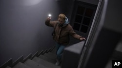 Anastasia Pyrozhenko, 25, climbs the stairs in her multistory apartment building in Kyiv, Ukraine, Nov. 20, 2022.