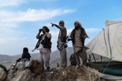 In this picture taken on July 15, 2021, Afghan militia fighters keep a watch at an outpost against Taliban insurgents at Charkint district in Balkh Province.