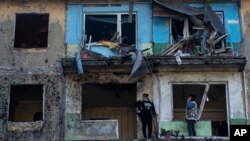 Local residents stand on the balconies of their apartments damaged by Russian shelling in Dobropillya, Donetsk region, eastern Ukraine, April 30, 2022.