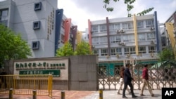 People walk past the gates of a closed primary school in Beijing, April 28, 2022. 
