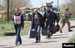 Civilians who left the area near Azovstal steel plant in Mariupol walk accompanied by a member of the International Committee of the Red Cross (ICRC) at a temporary accommodation center in the village of Bezimenne in the Donetsk Region, Ukraine, May 1, 2022.
