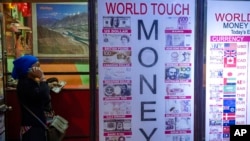 A Nepalese woman talks on a cellphone as she gets currency exchanged in Kathmandu, Nepal, April 15, 2022.