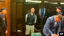 FILE - In this photo taken from video provided by the Moscow City Court, Ivan Safronov, an adviser to the director of Russia's state space corporation, center, stands in a court room during a court session in Moscow, Russia, Sept. 5, 2022. 