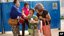 FILE - Bao Lanfang, second from right, whose daughter-in-law, son, and granddaughter were aboard Malaysia Airlines Flight 370, kneels in grief while speaking to journalists outside the company's offices in Beijing, Thursday, Aug. 6, 2015. 