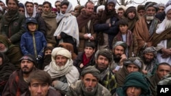 FILE - Hundreds of Afghan men gather to apply for humanitarian aid, in Qala-e-Naw, Afghanistan, Dec. 14, 2021.