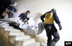 Members of Syrian civil defense known as the White Helmets, evacuate a body following an overnight raid by U.S. special operations forces against suspected jihadists in northwestern Syria, Feb. 3, 2022.