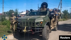 In this photo released by Ukraine's Security Service, Ukrainian service members patrol an area of the recently liberated town of Kupiansk, in Ukraine's Kharkiv region, amid Russia's invasion of Ukraine, Sept. 9, 2022. The soldiers' faces were blurred by the source.