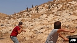 Warga Palestina melemparkan batu ke arah pasukan Israel menyusul protes terhadap pendirian pos-pos Israel, di Beit Dajan, timur Nablus, di Tepi Barat yang diduduki Israel, 9 September 2022. ( JAAFAR ASHTIYEH / AFP)