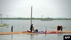 An internally displaced flood-affected man washes his clothes in a flood-hit area following heavy rains in Dera Allah Yar town of Jaffarabad district in Balochistan province, Pakistan, Sept. 8, 2022.