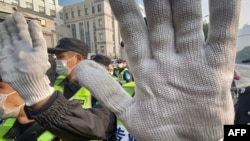 FILE - A policeman blocks the camera to stop journalists from recording footage outside the Shanghai Pudong New District People's Court, in Shanghai, Dec. 28, 2020.