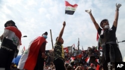 Anti-government protesters stand on barriers set up by Iraqi security forces to close the Joumhouriya Bridge leading to the Green Zone government area, in Baghdad, Iraq, Nov. 3, 2019.