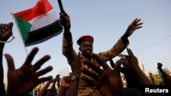 A Sudanese soldier sits on the shoulders of a demonstrator, cheering with the crowd outside Defense Ministry in Khartoum, Sudan, April 16, 2019.