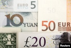 FILE - The Chinese yuan, shown Jan. 25, 2011, with the U.S. dollar, euro and British pound, is gradually moving to become a more market-oriented currency, and its international profile is growing.