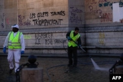 Workers clean around the Arc de Triomphe a day after a yellow vests (gilets jaunes) demonstration against rising oil prices and living costs, Dec. 2, 2018 in Paris. Graffiti on the monument reads "yellow vests will triumph."