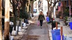 A woman walks past trash that is sitting out for collection in Philadelphia, Jan. 13, 2022.