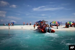 FILE - Chinese tourists enjoy scenic Quanfu Island, one of Paracel Islands of Sansha prefecture of southern China's Hainan province, Sept. 14, 2014.
